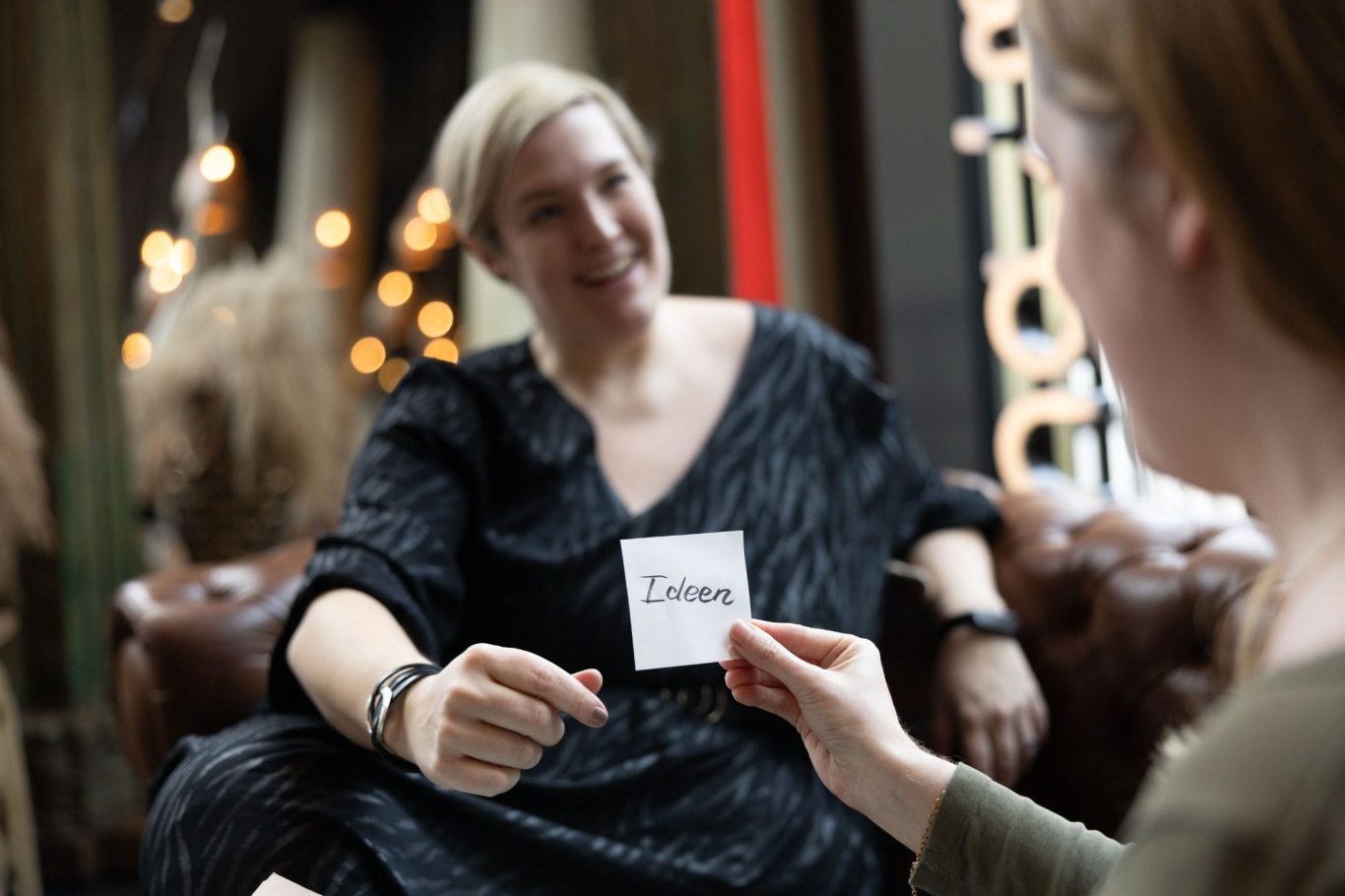 Individuelles Coaching für Studierende – psychologische Beratung bei Stress und Entscheidungsfindung Eine Person hält eine Karte mit dem Wort "Ideen" in einem gemütlichen Café.